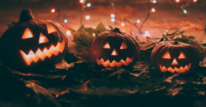 three pumpkins with faces carved into them with lights in the background.